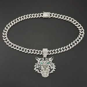 Detail von silbernem Tigerkopf-Anhänger mit grünen Augen und Iced-Out-Cuban-Halskette