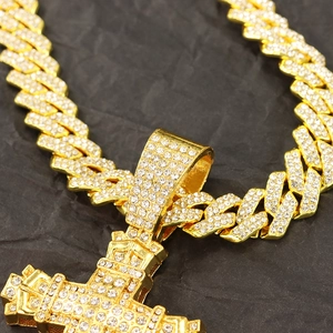 Macro d'un pendentif croix hip-hop doré et d'une chaîne à maillons cubains sertie de diamants