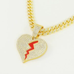 Vue macro d'un pendentif hip-hop coeur rouge et d'une chaîne à maillons cubains dorée