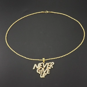 Gros plan du pendentif NEVER GIVE UP doré serti de zircons brillants sur chaîne torsadée