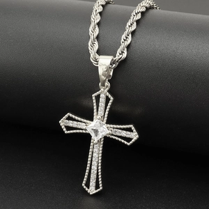 Dettaglio di un ciondolo a croce in argento con zirconi su una catena a corda intrecciata