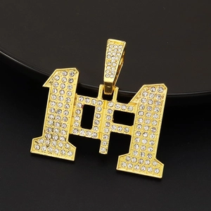 Dettaglio del ciondolo numero 191 dorato con strass scintillanti su sfondo nero puro