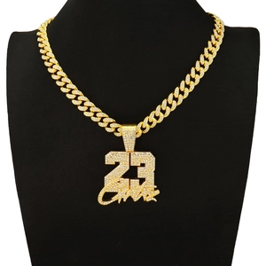 Macro shot of iced-out number 23 pendant with GOAT signature on golden Cuban link chain