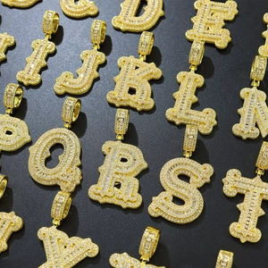 Gros plan de pendentifs lettres dorés sertis de cristaux baguette effet iced out