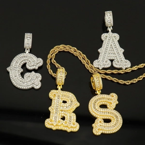 Détail de pendentifs lettres hip hop sertis de cristaux sur une chaîne de corde dorée