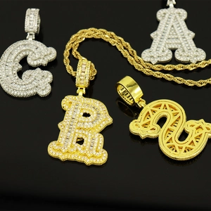 Détail de pendentifs lettres hip hop sertis de strass sur une grosse chaîne en or