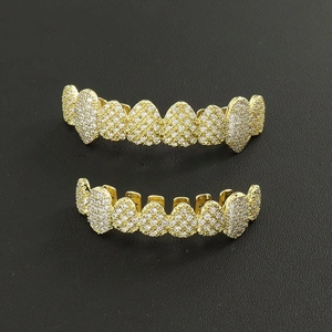 Close-up of gold-plated hip hop grillz set with pavé cubic zirconia on black texture