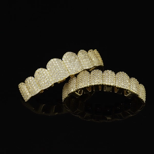 Close-up of iced out gold plated copper grillz set with cubic zirconia stones on black base