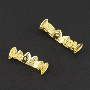 Détail de grillz hip hop dorés avec motifs d'étoiles et points creux sur fond noir mat