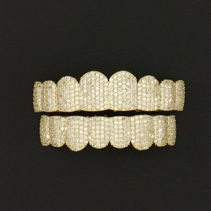 Hip hop gold plated copper grillz set with zircon stones on a black leather background