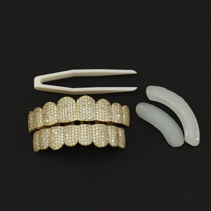 Close-up of gold-plated hip hop grillz set with cubic zirconia stones and fitting tools