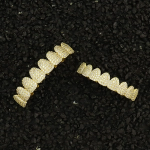 Dettaglio del set grillz hip hop dorato con zirconi scintillanti su pietre nere