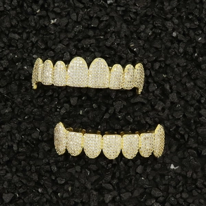 Detailed view of hip hop gold grillz set with white zirconia on black stone surface