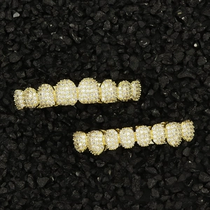 Close-up of gold hip-hop grillz with white zircons on black rock background