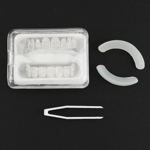 Detailed set of iced-out silver fangs with fixing bars, tweezers, and a clear storage case