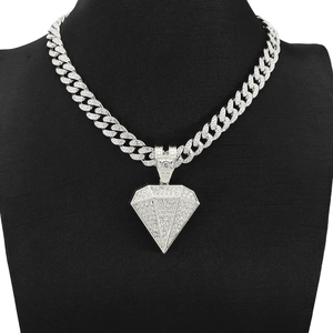 Macro-opname van een zilveren piramidehanger met diamanten op een Cuban link ketting