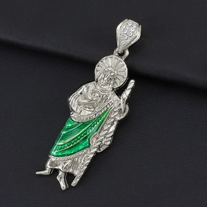 Macro shot of silver religious St. Jude pendant with green enamel and crystal stones