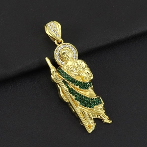 Detailed macro view of St. Jude gold pendant with green gems on black leather base