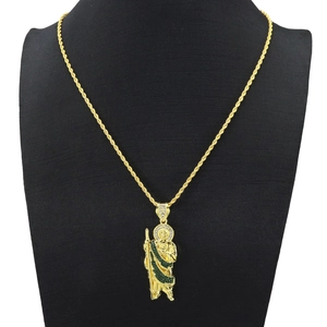 Close-up of golden Saint Jude pendant necklace with green and white crystals on a rope chain
