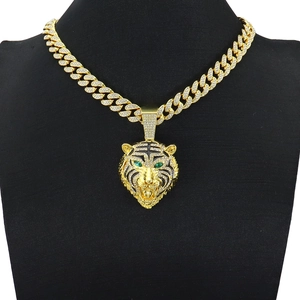 Détail du pendentif tête de tigre doré serti de strass avec des yeux verts brillants