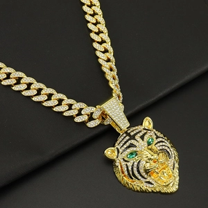 Gros plan du pendentif tête de tigre aux yeux verts et chaîne cubaine sertie de diamants