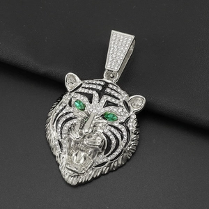 Détail du pendentif tête de tigre argenté avec yeux verts et strass brillants