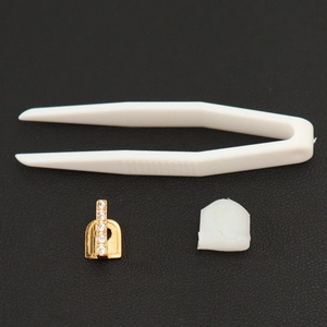 Détail du grillz hip-hop doré avec zircons, barre de silicone et pince blanche