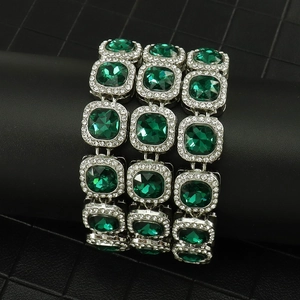 Detail view of cushion-cut green gemstones on silver iced out cuban chain necklace