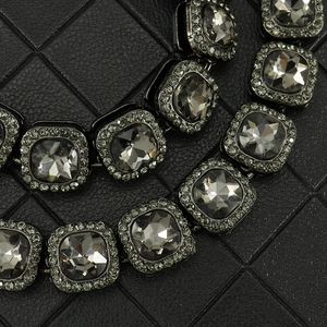 Détail du collier avec strass gris foncé taille carrée et bordure pavée sur base noire
