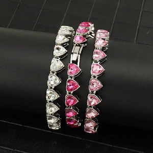 Nahaufnahme von herzförmigen Kristall-Tennisarmbändern in Silber, Rosa und Rot auf Ständer