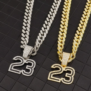 Close-up of gold and silver iced out number 23 pendants on diamond Cuban link chains