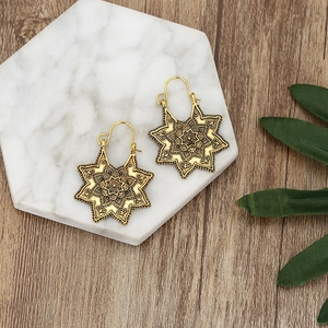 Boucles d'oreilles bohèmes vintage dorées avec mandala sur plateau en marbre