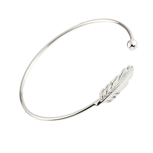 Delicate open silver feather bangle with leaf engraving and metal bead accent on white background