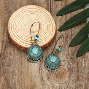 Orecchini vintage in bronzo con pietre turchesi su sfondo di legno naturale