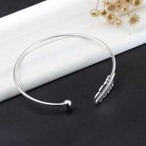 Detail shot of open cuff bracelet with engraved leaf design and polished bead terminal