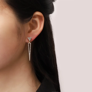 Gros plan de boucles d'oreilles géométriques en triangle doré avec cristaux brillants