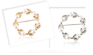 Détail de la broche couronne avec perles blanches et gravure de feuilles en or et argent
