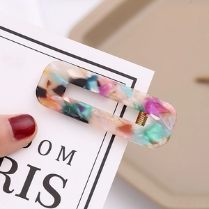 Macro shot of rectangular acetate hair clip with colorful marble pattern and gold metal spring