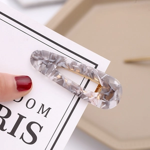 Close-up of marble acetate hair clip with gold metal base and retro tortoiseshell pattern