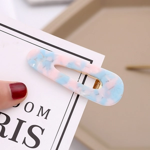 Close-up of pink and blue marbled acetate hair clip with golden metal fastener detail