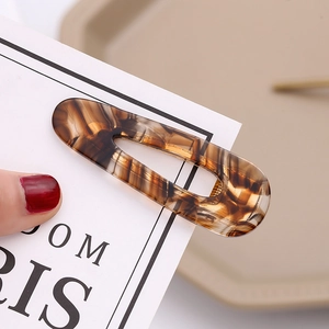 Macro shot of polished amber tortoiseshell hair clip showing textured cellulose acetate material