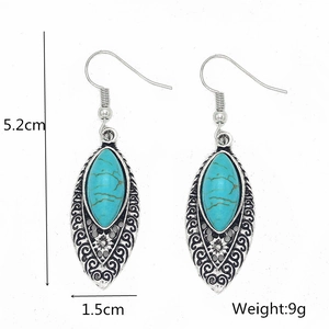 Detailed view of bohemian turquoise drop earrings with silver floral patterns and dimensions