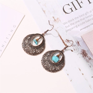 Dettaglio di orecchini boho in rame con intagli cavi e pietra di turchese blu naturale