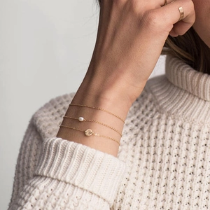 Detailed close-up of a three-piece gold layered bracelet set with letter A round pendant