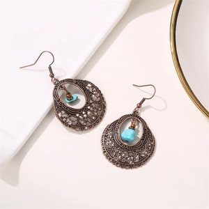 Dettaglio di orecchini vintage in rame con incisione cava, pietra turchese e design boho