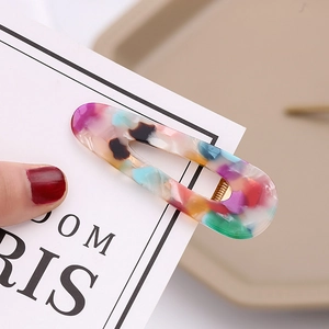 Detailed view of acetate hair clip with colorful leopard marble pattern and gold metal base