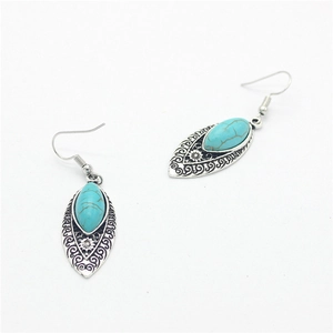 Detail view of retro alloy teardrop earrings with turquoise stones on white background