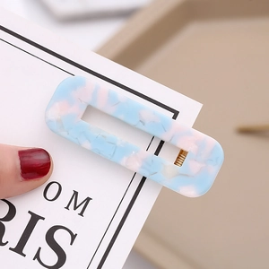 Detail view of blue and pink marble acetate hair clip with golden metal clip on card