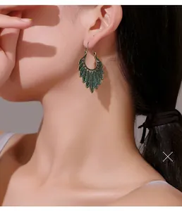 Detail view of vintage bronze leaf earrings with green enamel and boho feather design