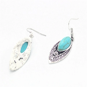Detail of bohemian silver finish drop earrings with turquoise stone and floral patterns